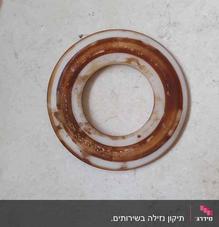 אטם עגול עם כתמים חומים על רצפה בהירה